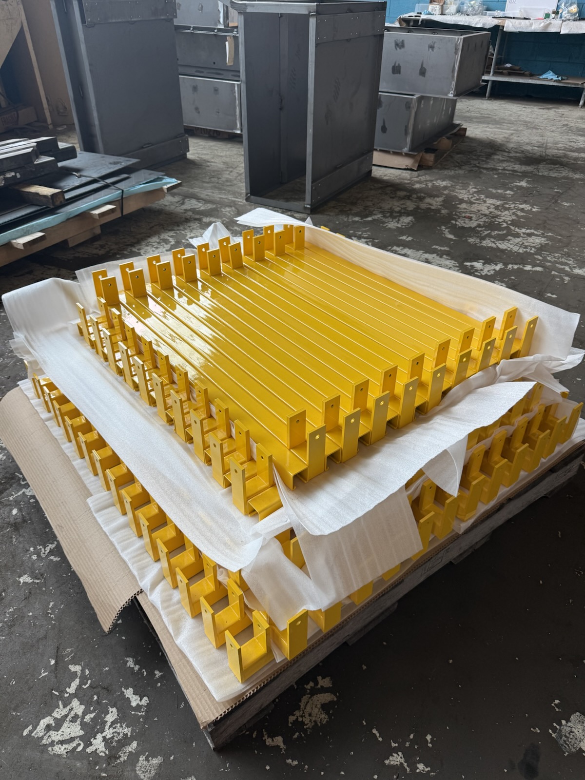 Batch of yellow powder coated steel brackets